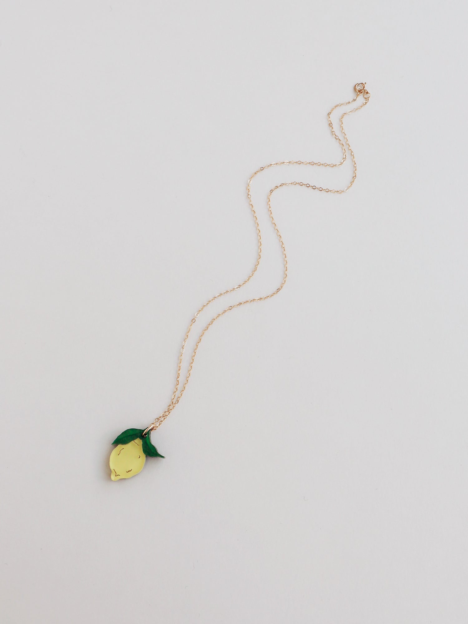 Lemon pendant necklace with green leaf made with wood, 64% recycled acrylic and hand-inked details. Hung on a high quality 45cm gold-filled chain. Handmade in the UK by Wolf & Moon.