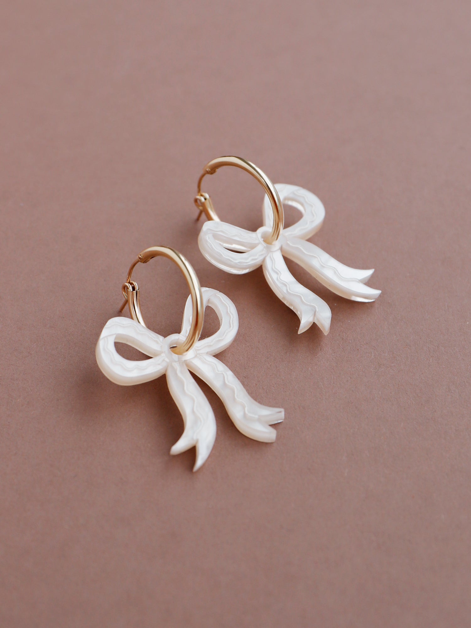 Romantic mini bow earrings in off-white made from velvety marbled acrylic with hand-inked details. Surprisingly lightweight so can be worn for extended periods of time. Each bow is hand-sculpted into a 3D form giving it a lovely realistic ribbon-like effect. This also adds a unique charm to each one. Handmade by Wolf & Moon in the UK. ⁠