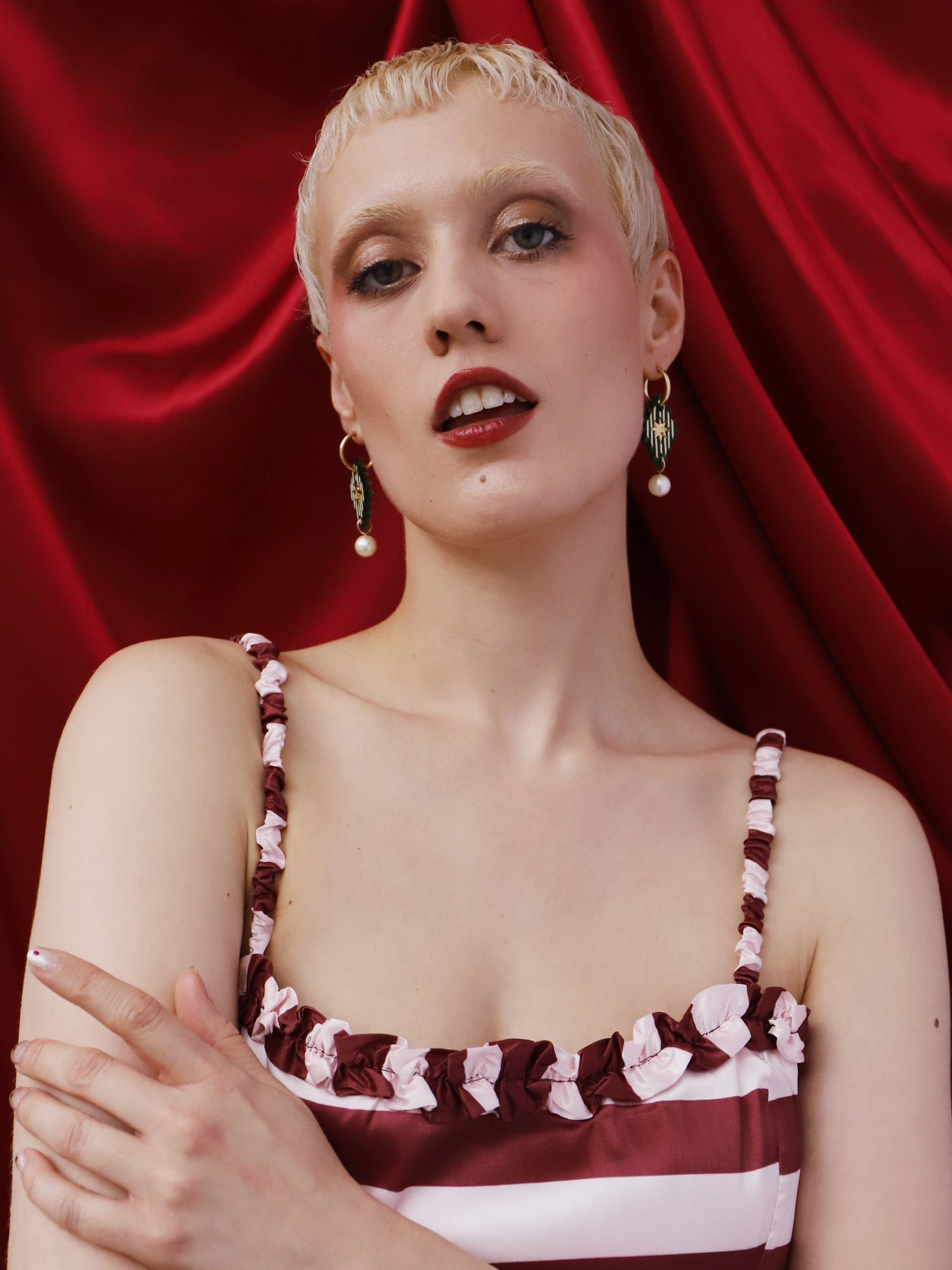 Model wearing Cirque Hoops in Jade earrings with a red satin background, showcasing handmade design elegance.