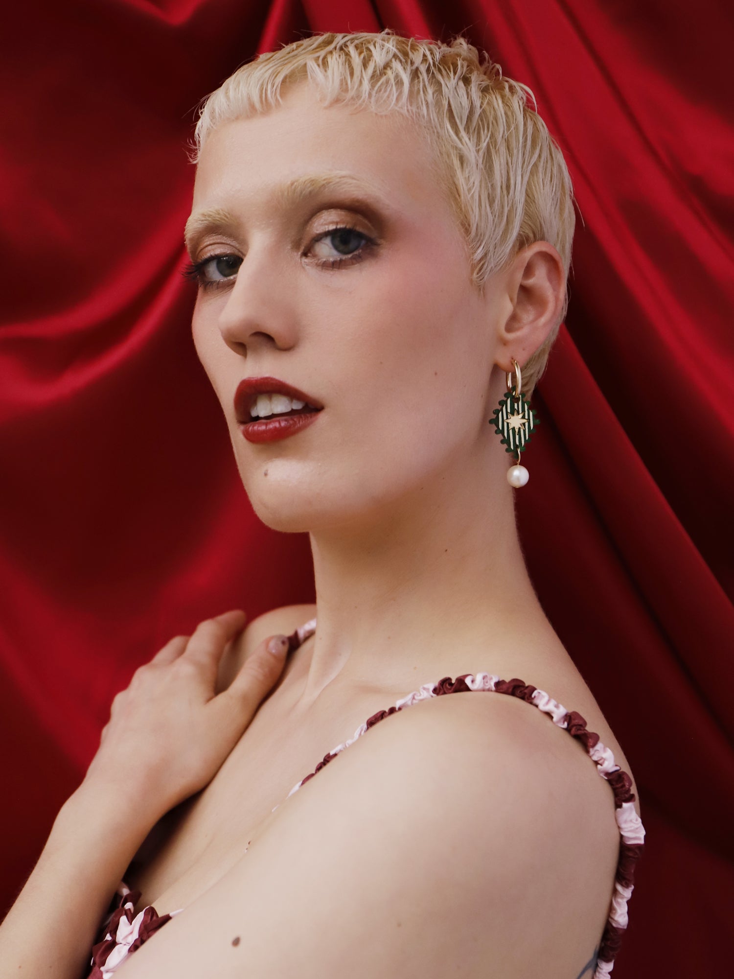 Model showcasing Cirque Hoops in Jade earrings by Wolf & Moon, handmade in UK, against a red backdrop.