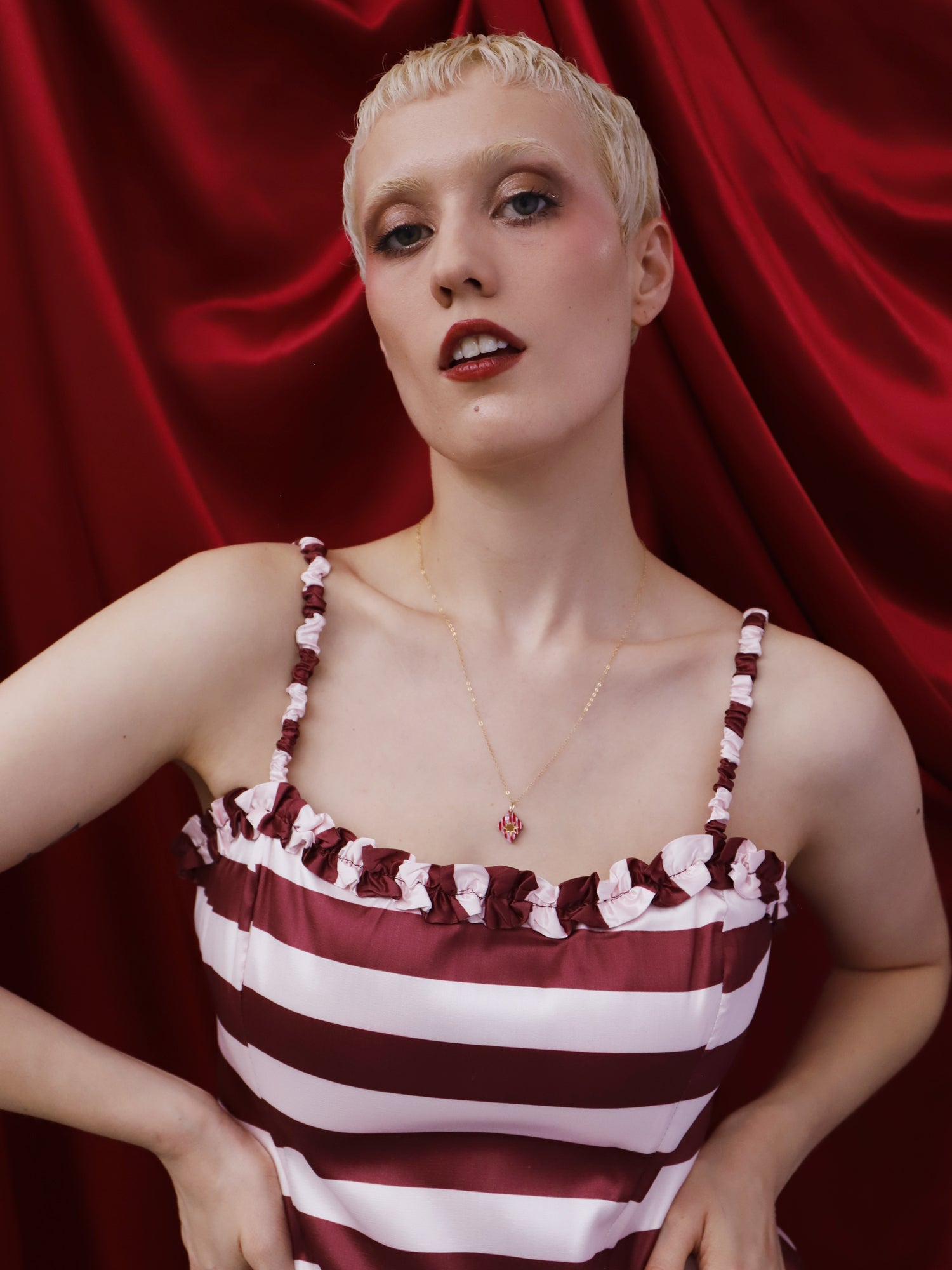 Model wearing the Nova Necklace in Rose against a red backdrop, showcasing the unique design and handmade details by Wolf & Moon.