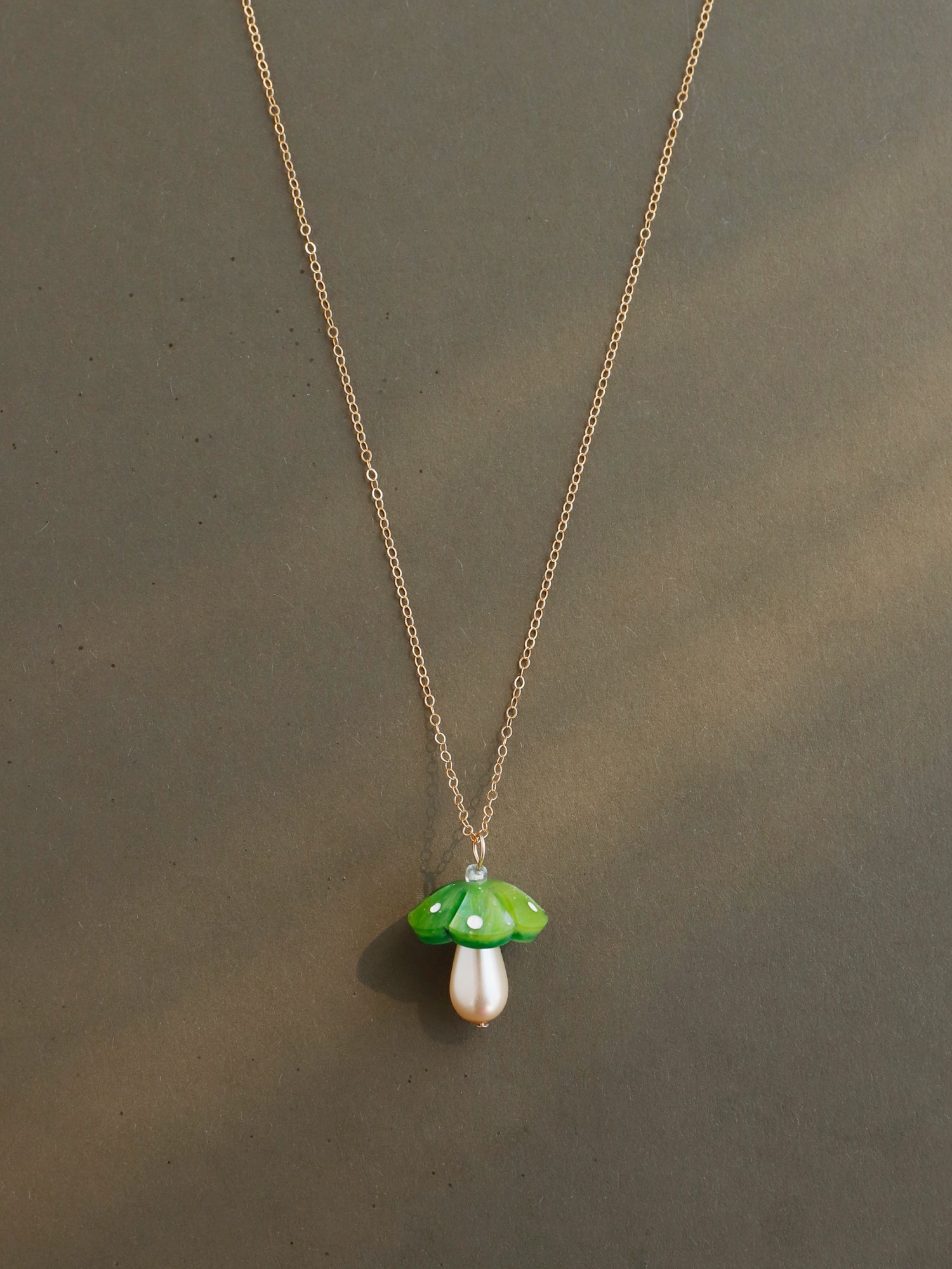 Green mushroom pendant necklace. Made from heat-formed acrylic with hand-inked details and finished off with a high quality Czech glass pearl. Pendant is hung on a high quality 50cm 14k gold-filled chain. Handmade in the UK by Wolf & Moon.