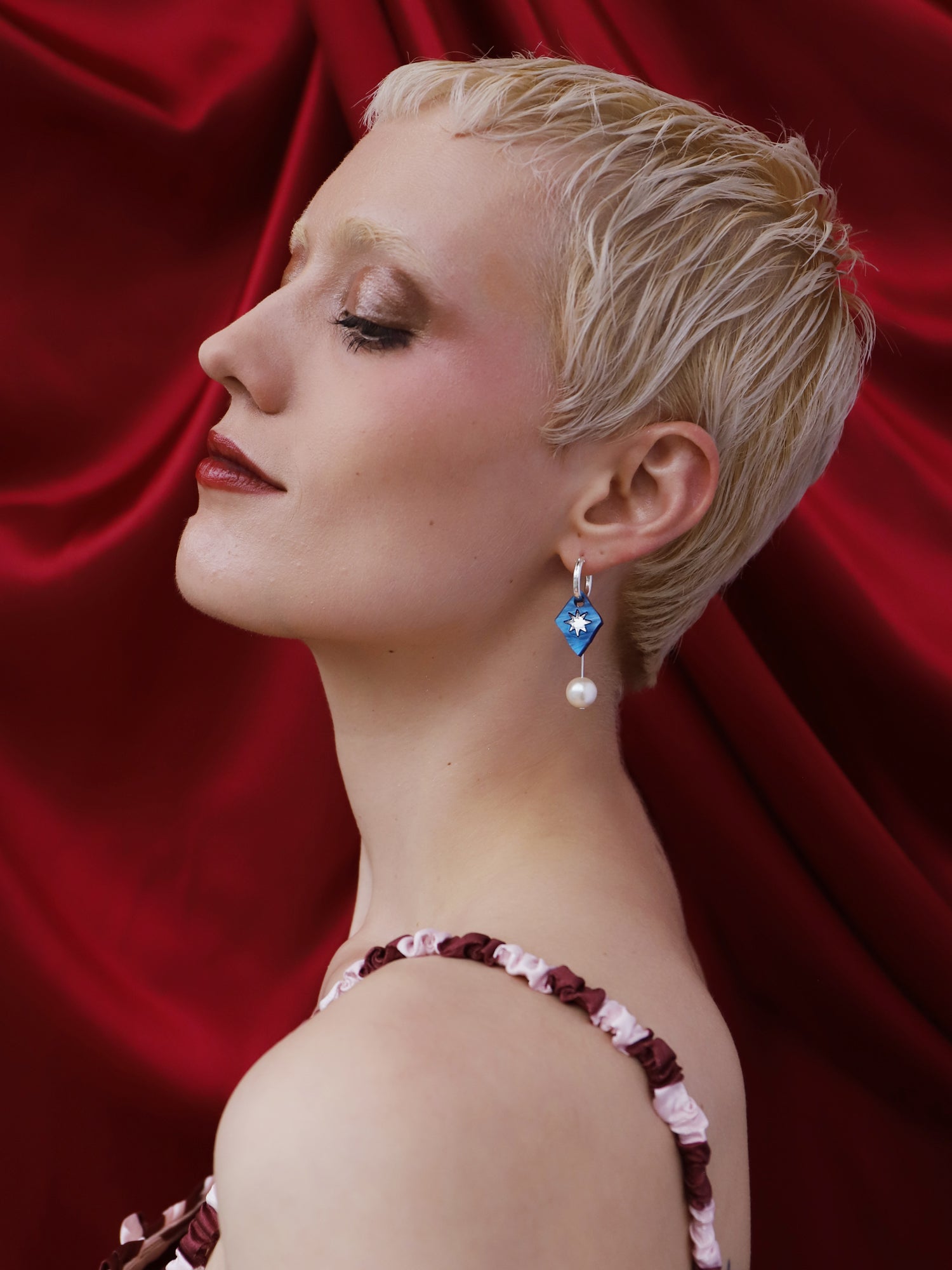 Model showcasing Stella Charm Hoops in Sapphire, handmade in UK by Wolf & Moon, featuring blue charms and pearl details.