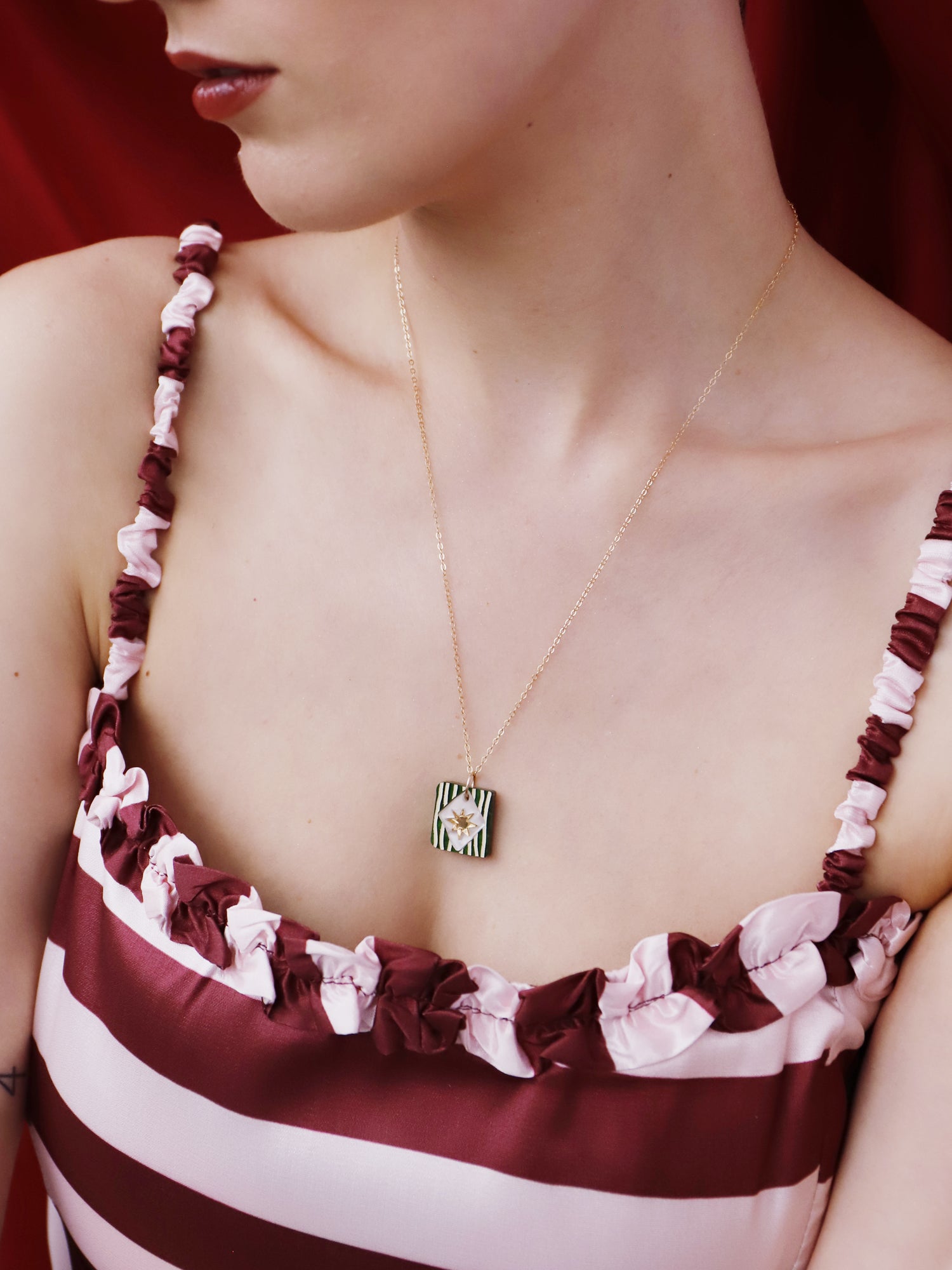 Stella Necklace in Jade worn by a model with striped top, showcasing unique design and hand-inked details.