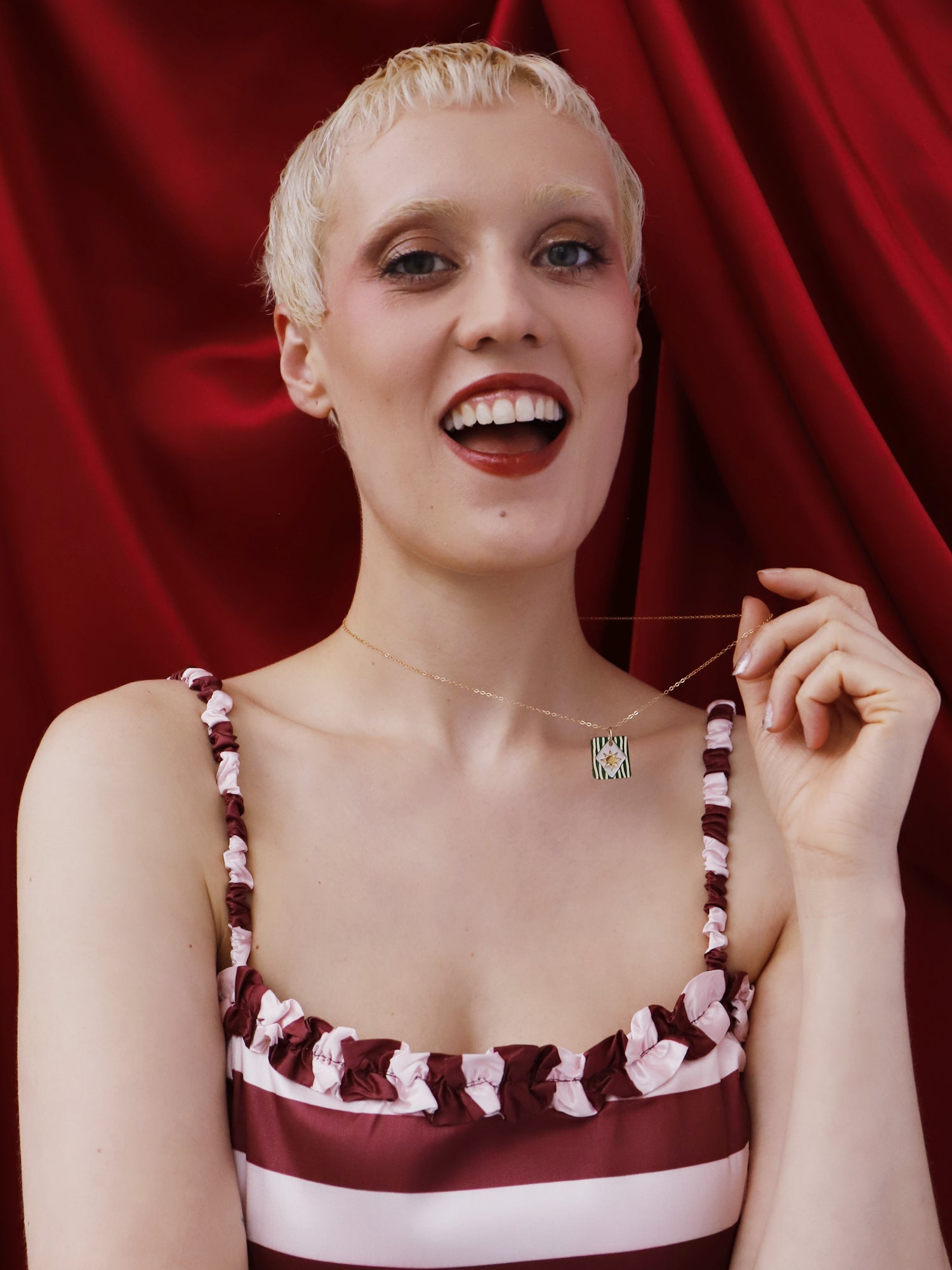 Model showcasing Stella Necklace in Jade against burgundy backdrop, emphasizing its unique design and elegance.