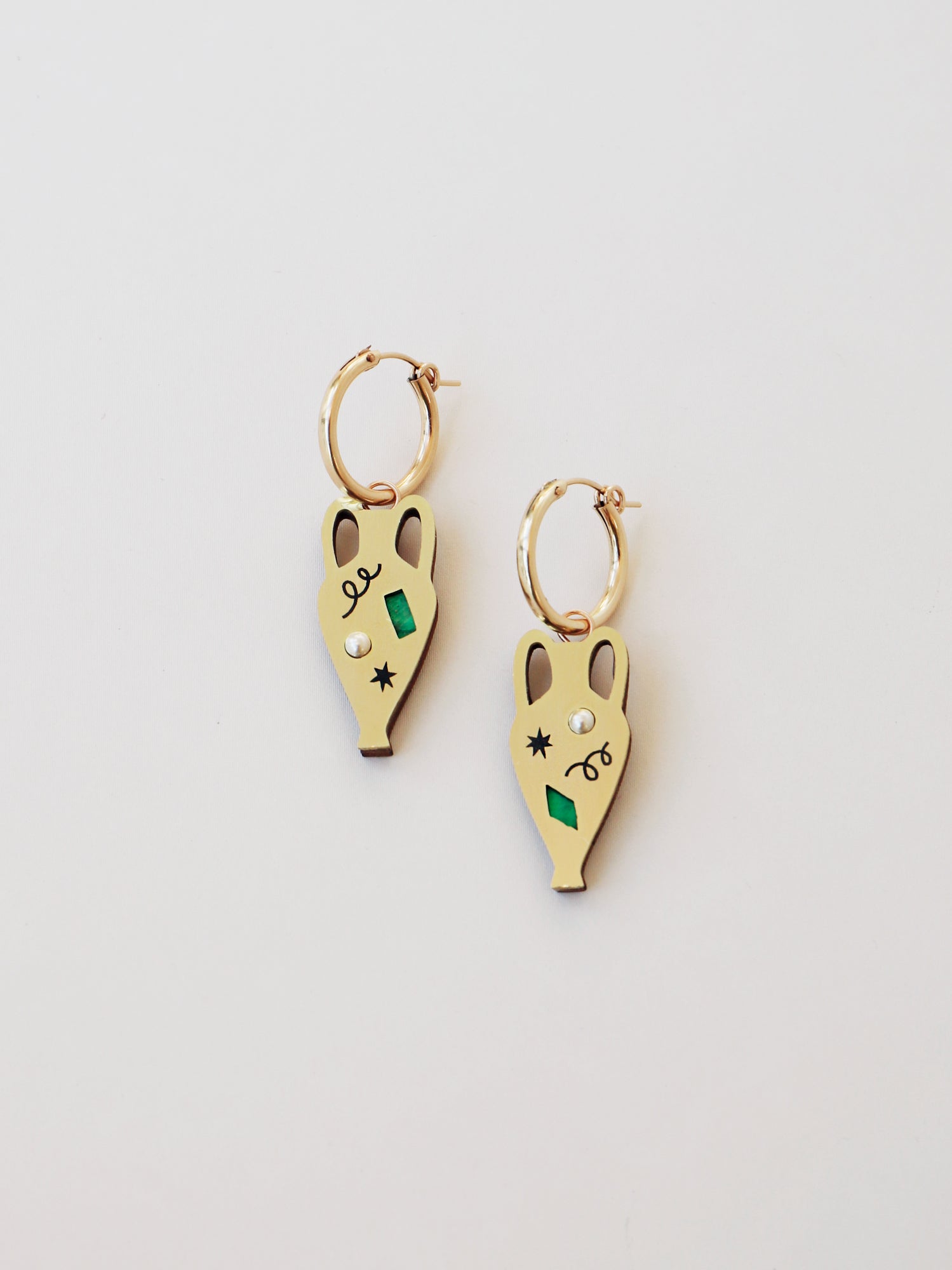 Brass vase shape hoop earrings. Glass pearls and abstract cut outs with inlaid shell and illustrative detailing.