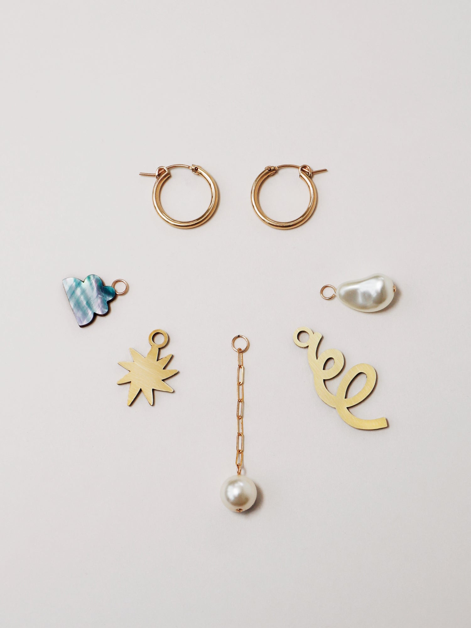 Confetti Charm Hoops in Brass. A playful mix 'n' match hoops set with 5 interchangeable charms including our curly wurly pieces, Czech glass baroque pearls, 14k gold-filled chain and sterling silver earring posts. Made in the UK by Wolf & Moon.