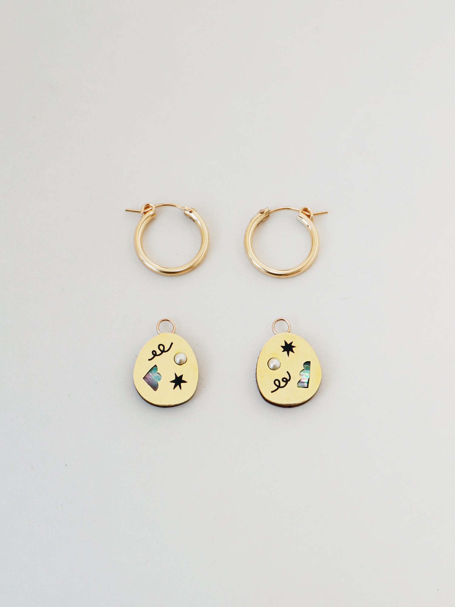 Elegant brass hoop earrings with an illustrative design inspired by celebrations & confetti. Glass pearls and abstract cut outs with inlaid shell in emerald green. Handmade in the UK by Wolf & Moon.