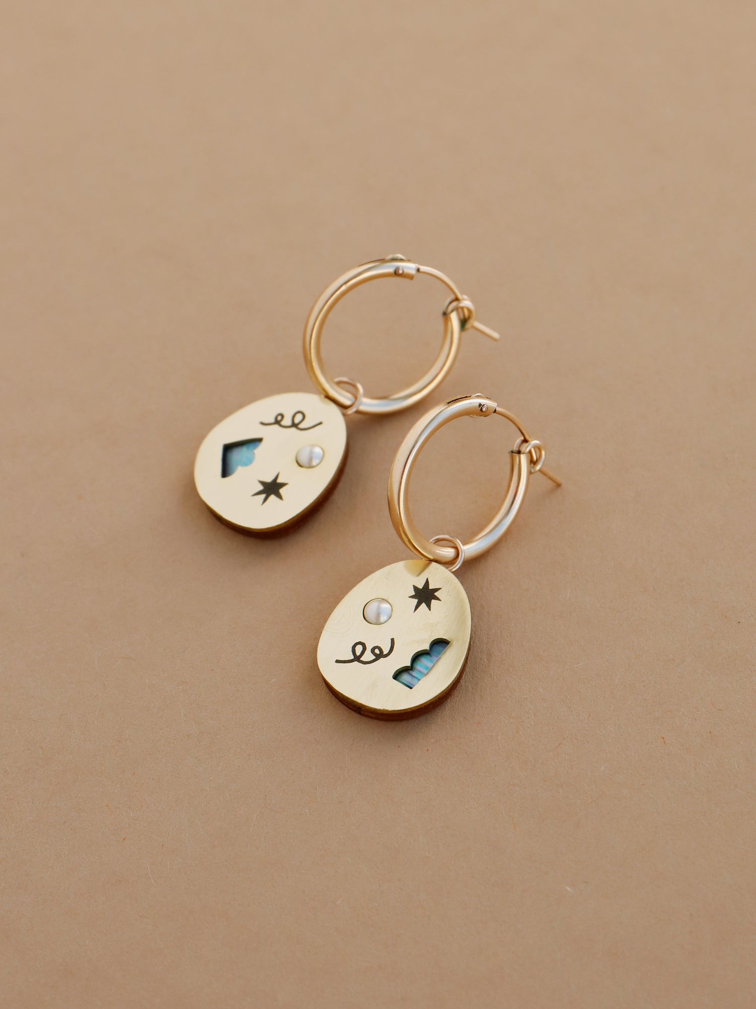 Elegant brass hoop earrings with an illustrative design inspired by celebrations & confetti. Glass pearls and abstract cut outs with inlaid shell in emerald green. Handmade in the UK by Wolf & Moon.