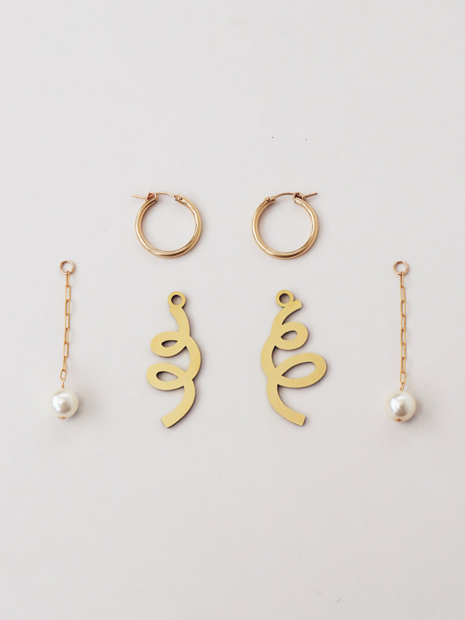 Lola Charm Hoops in Brass. Mix 'n' match curly brass charms and Czech glass baroque pearls on a paperclip gold-filled chain with sterling silver earring posts. Made in the UK by Wolf & Moon.