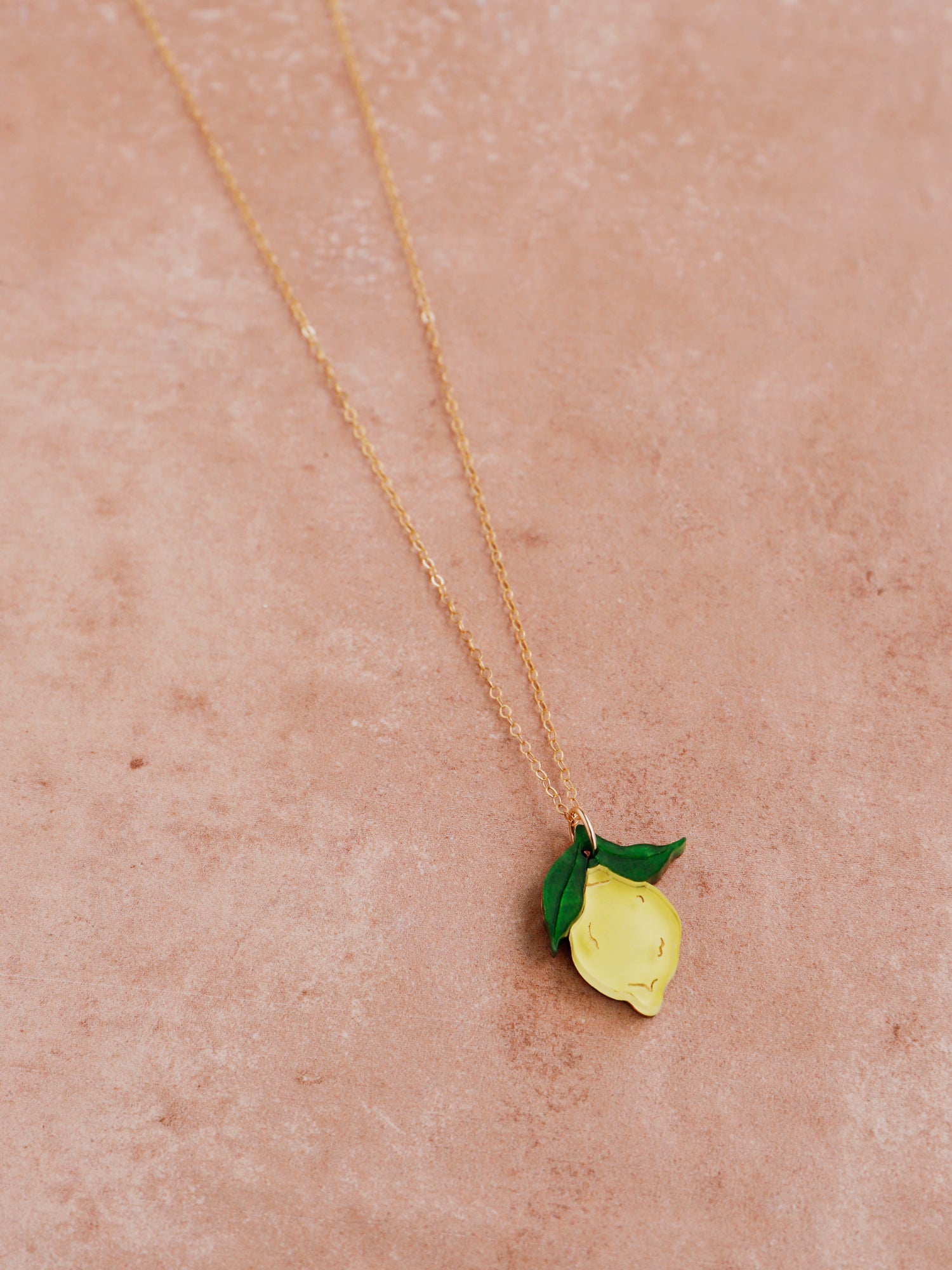 Lemon pendant necklace with green leaf made with wood, 64% recycled acrylic and hand-inked details. Hung on a high quality 45cm gold-filled chain. Handmade in the UK by Wolf & Moon.