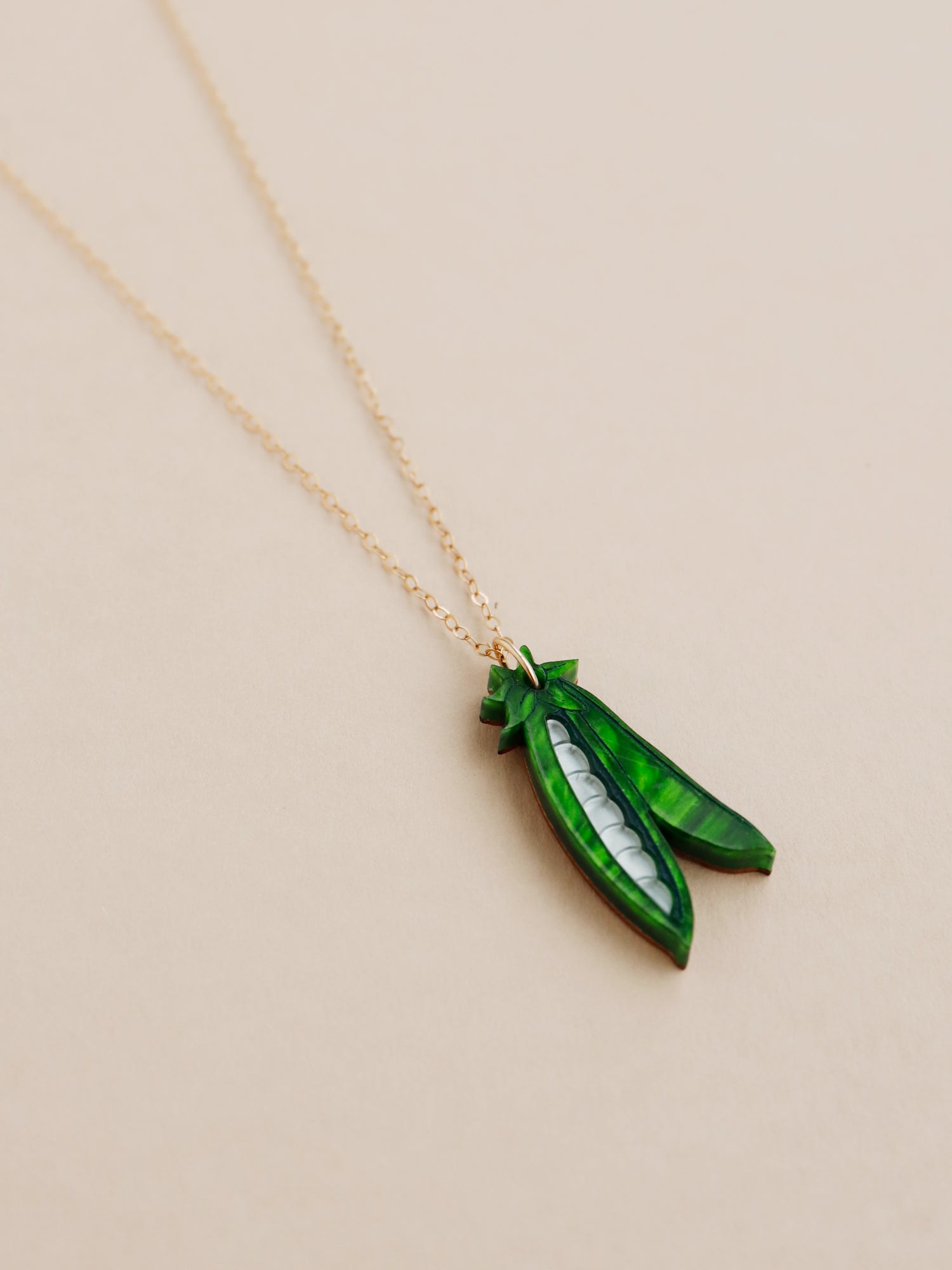 A playful peas in a pod pendant made from marbled acrylic and wood with an optional 14k gold-filled chain. Handmade in London by Wolf & Moon.