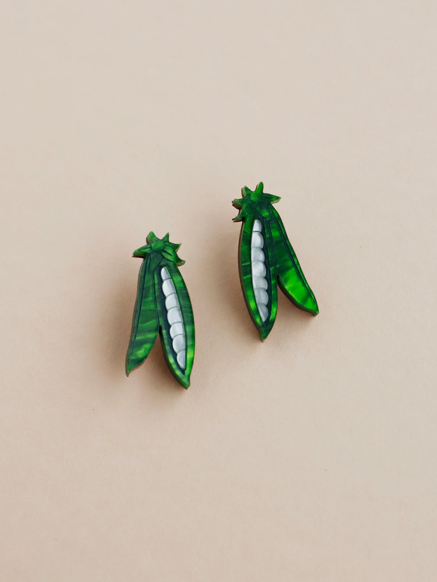 These playful peas in a pod stud earrings are made from marbled acrylic, wood with sterling silver posts. Handmade in London by Wolf & Moon.