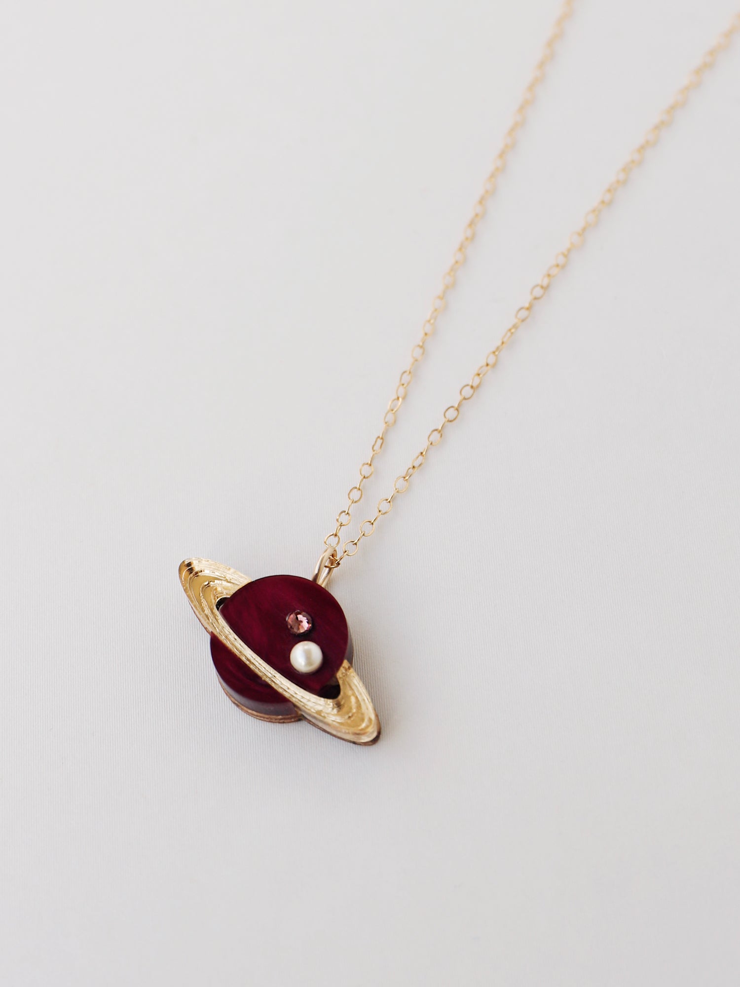 Saturn pendant necklace in pearlescent cherry acrylic, embellished with high quality glass pearls & crystals. Wear with our 14k gold-filled chain. Handmade in London by Wolf & Moon.