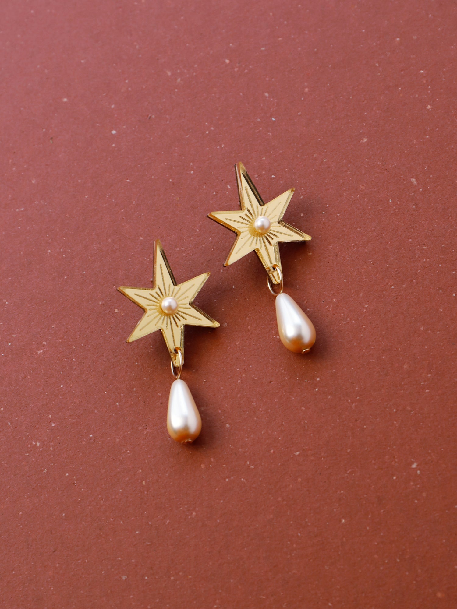 Statement star studs made with gold mirrored acrylic, embellished with glass pearl and bead details. Handmade in London by Wolf & Moon.