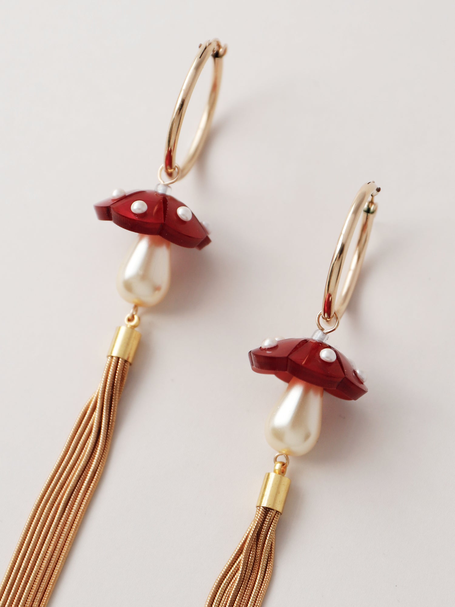Marbled red acrylic statement mushroom hoops with gold plated snake chain tassels. Finished with high quality Czech glass pearls. Handmade by Wolf & Moon.